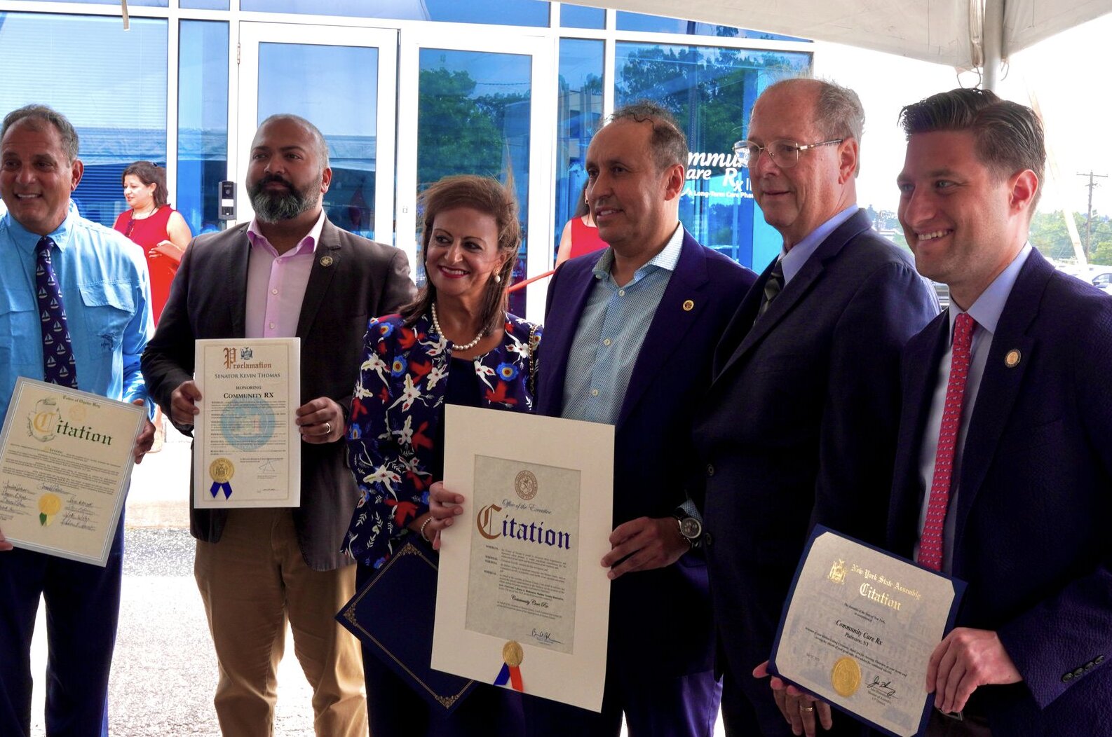 Community Care Rx team members and elected officials holding citations honoring the pharmacy