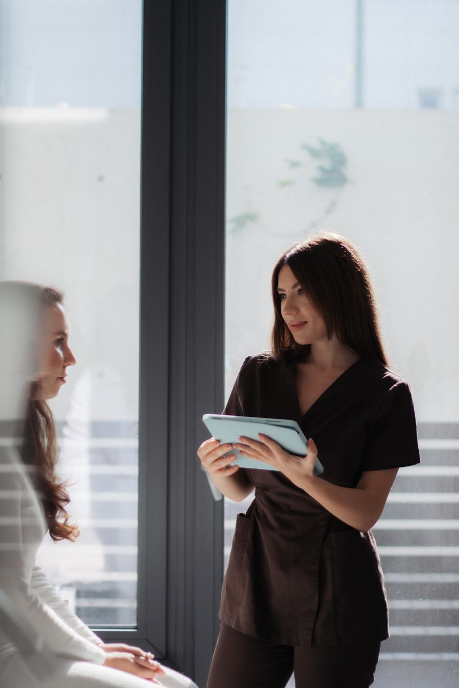 A professional in scrubs holding a tablet during a consultation