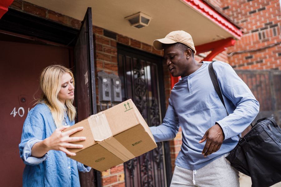 A courier handing a sealed box to a woman at her doorway