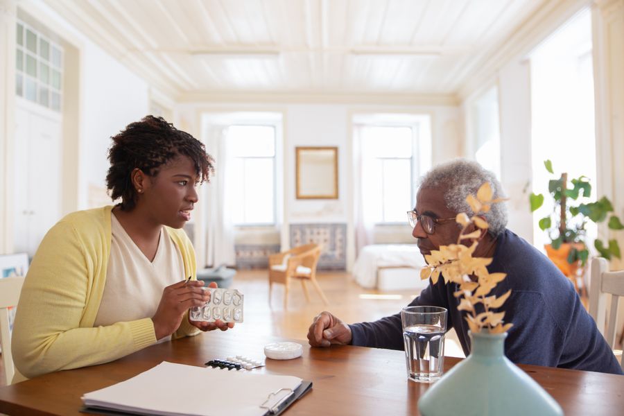 Two adults discussing a medication blister pack at a table at home